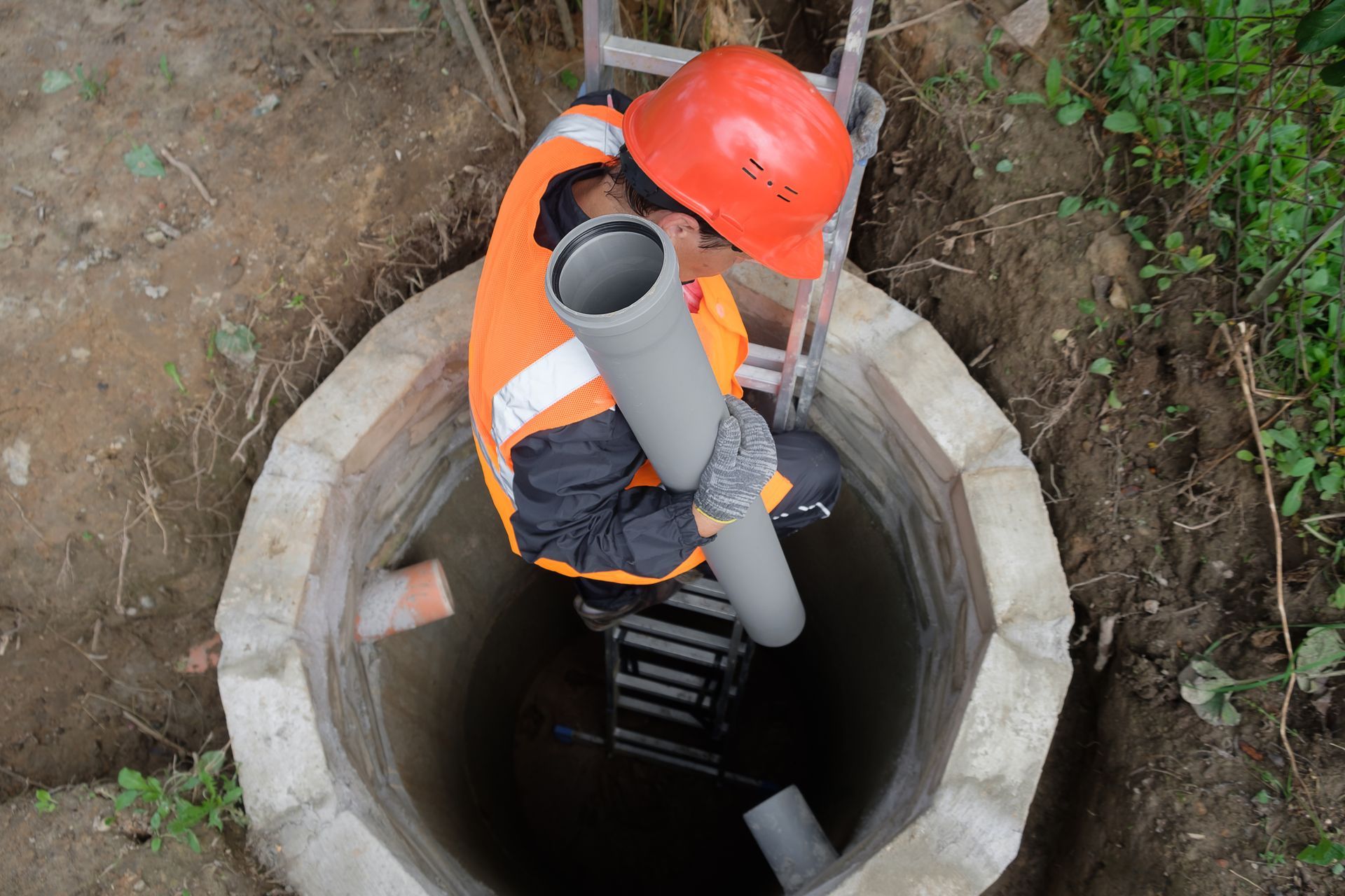 Worker installing septic system pipes, showcasing septic system repair at a private house.
