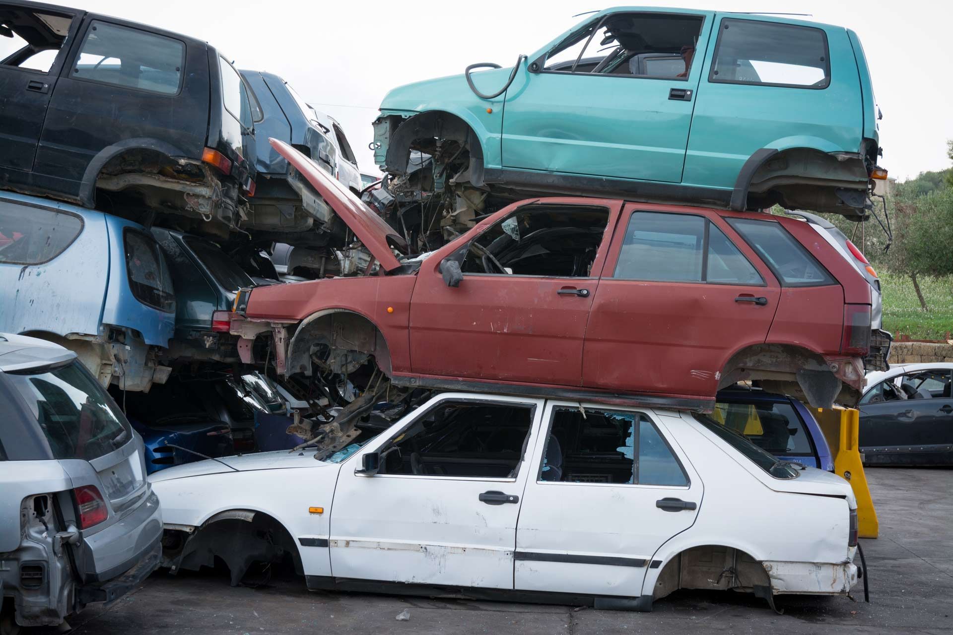 A pile of cars are stacked on top of each other in a junkyard.