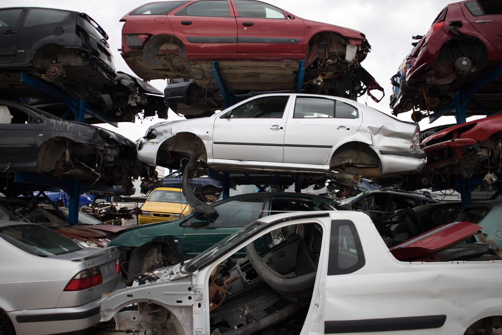 A bunch of cars are stacked on top of each other in a junkyard.