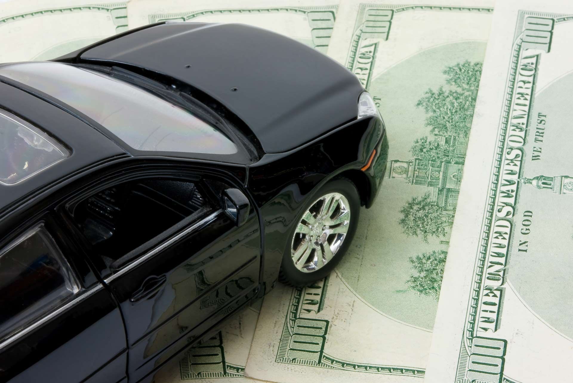 A black car is sitting on top of a pile of 20 dollar bills
