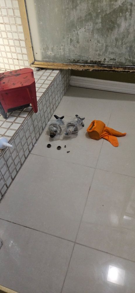 A white tiled floor with a red stool and a towel on it.