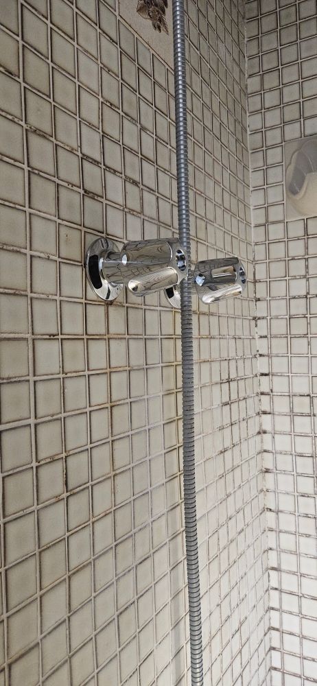 A shower head is hanging on a tiled wall in a bathroom.