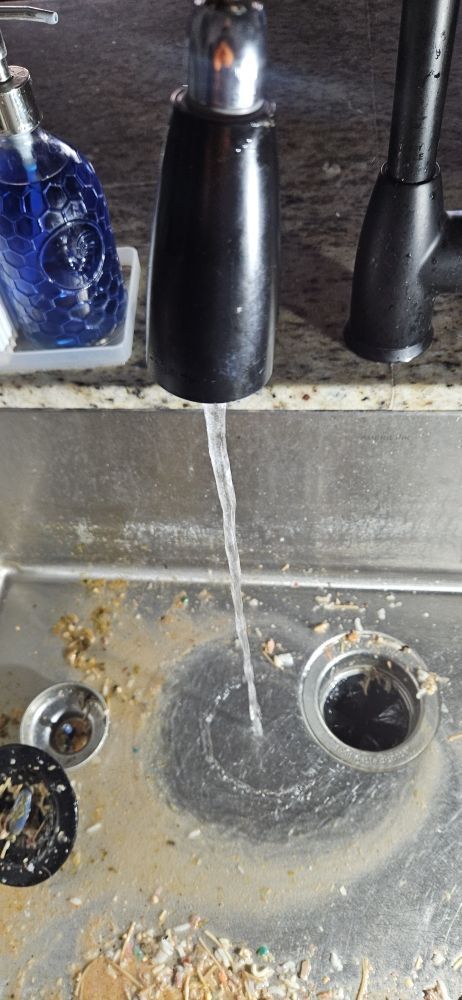 A close up of a sink with water coming out of the faucet.