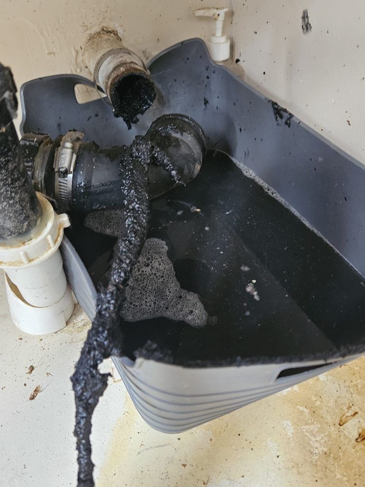 A sink with a lot of black liquid coming out of it.