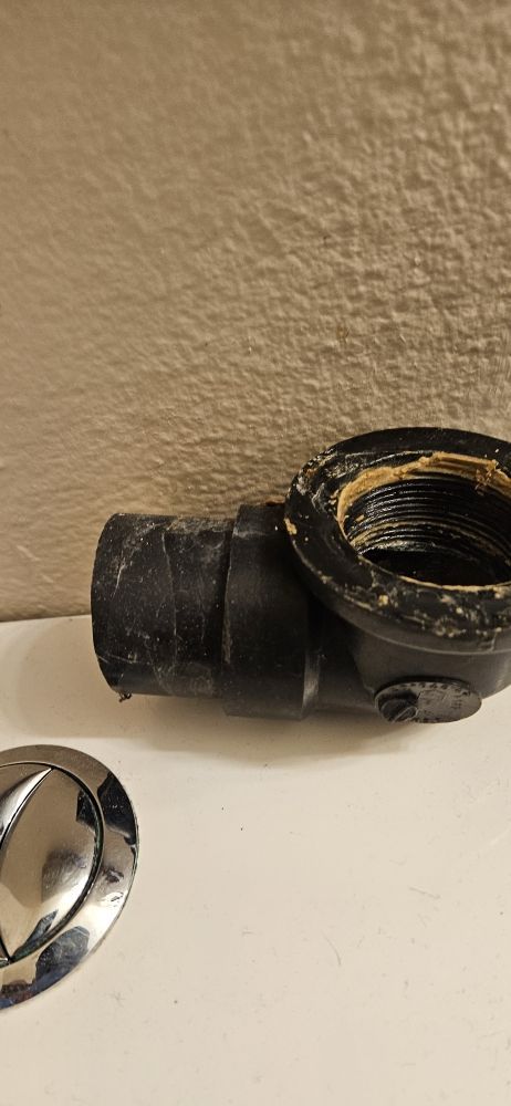 A black pipe is sitting on top of a white counter next to a drain.