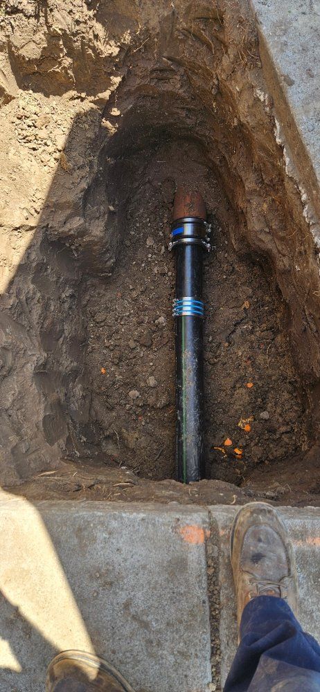 A person is standing next to a pipe in the dirt.