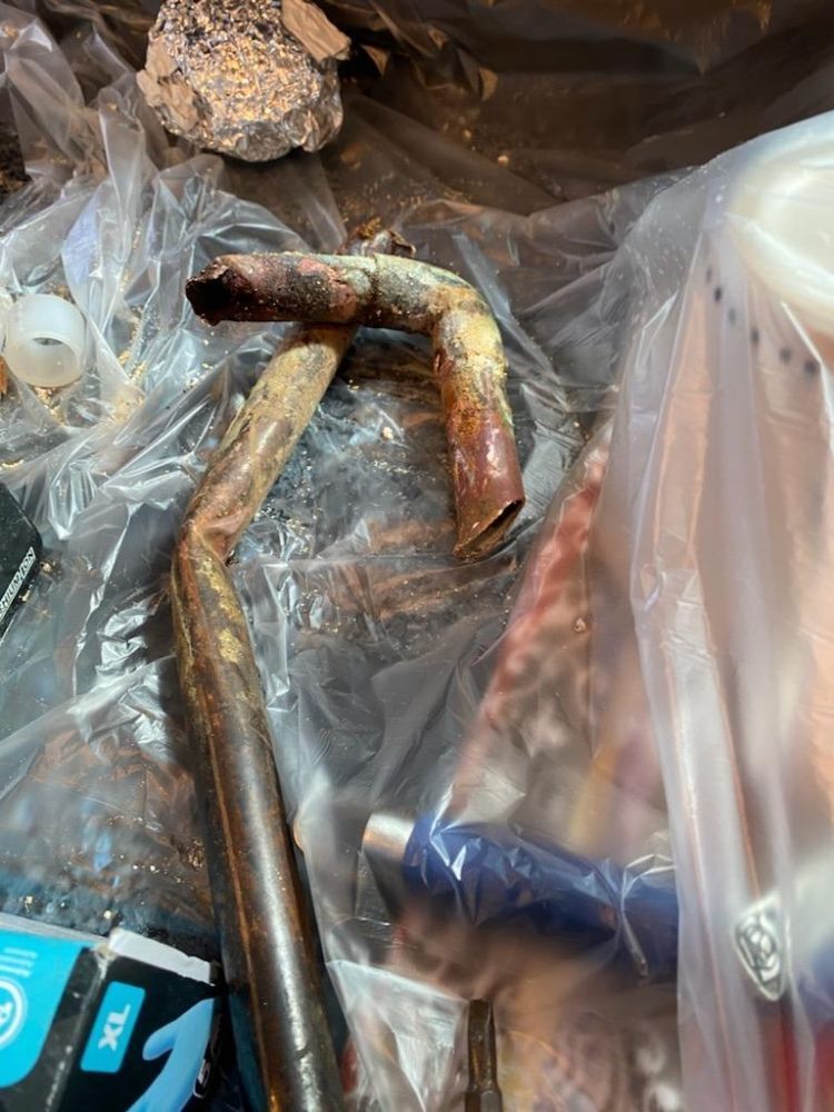 A rusty pipe is sitting on top of a plastic bag.