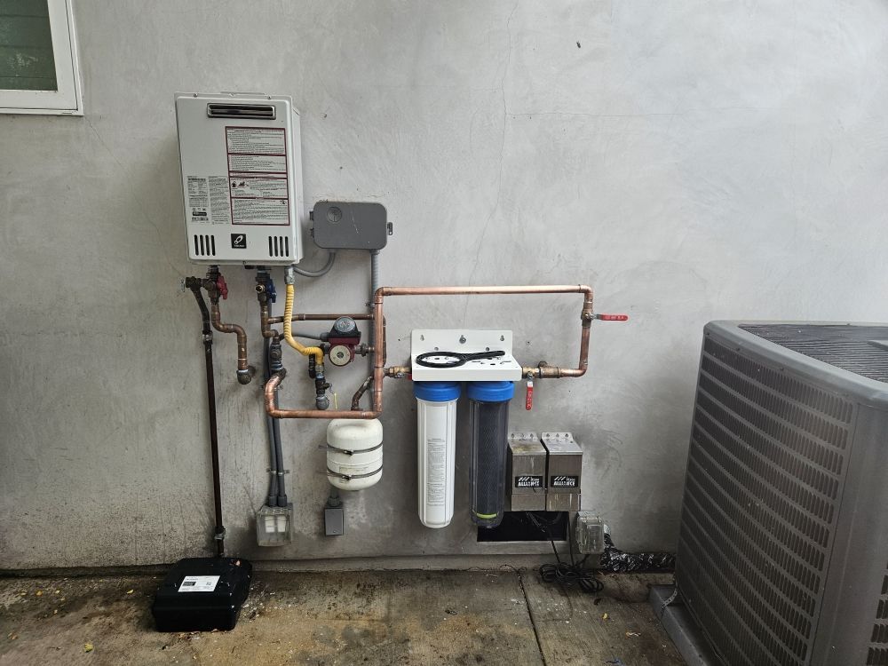 A water heater is attached to a wall next to an air conditioner.