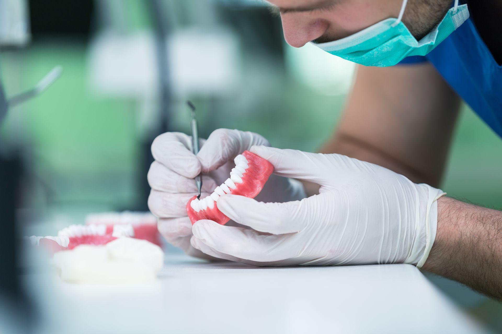 dental implants lab technician shaping denture model with tools in sterile workspace. dental implants lab technician shaping denture model with tools in sterile workspace.