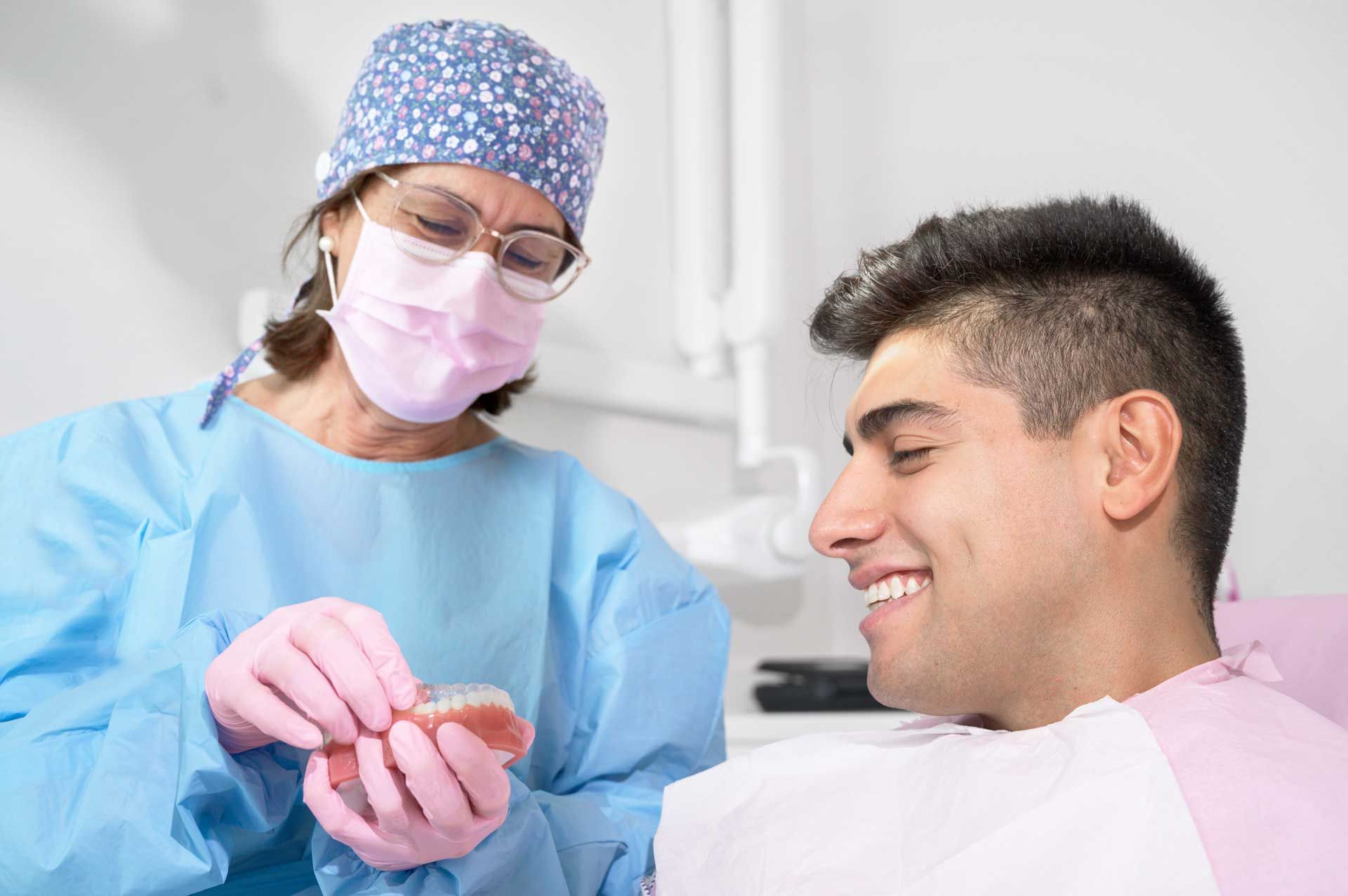 Dentist showing dentures to a smiling patient in a dental office.