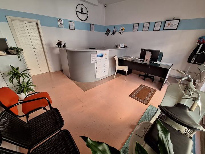 Area reception con scrivania curva, scrivania con computer, sedie per i visitatori e vari elementi decorativi alle pareti.