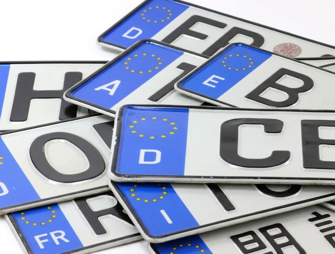 Una collezione di targhe automobilistiche tedesche sovrapposte con strisce blu di identificazione dei paesi dell'UE.