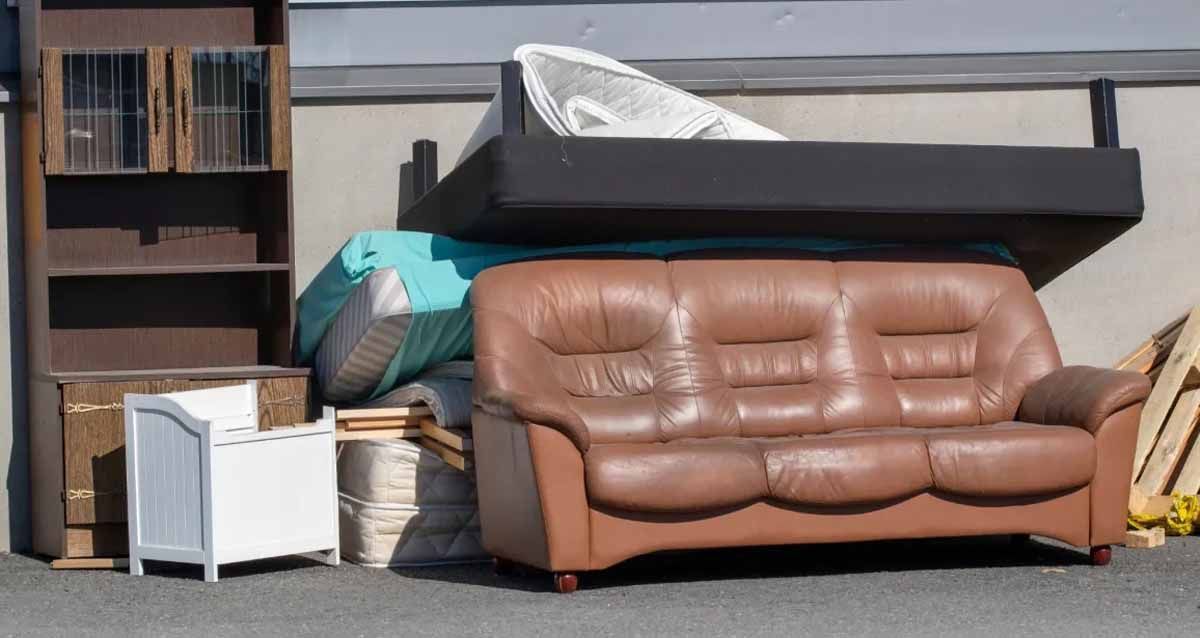 A brown leather couch is sitting on top of a pile of furniture.