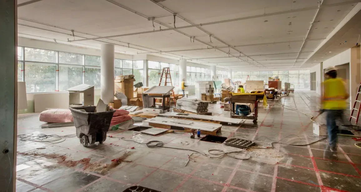 A large room is being remodeled with a lot of construction workers.