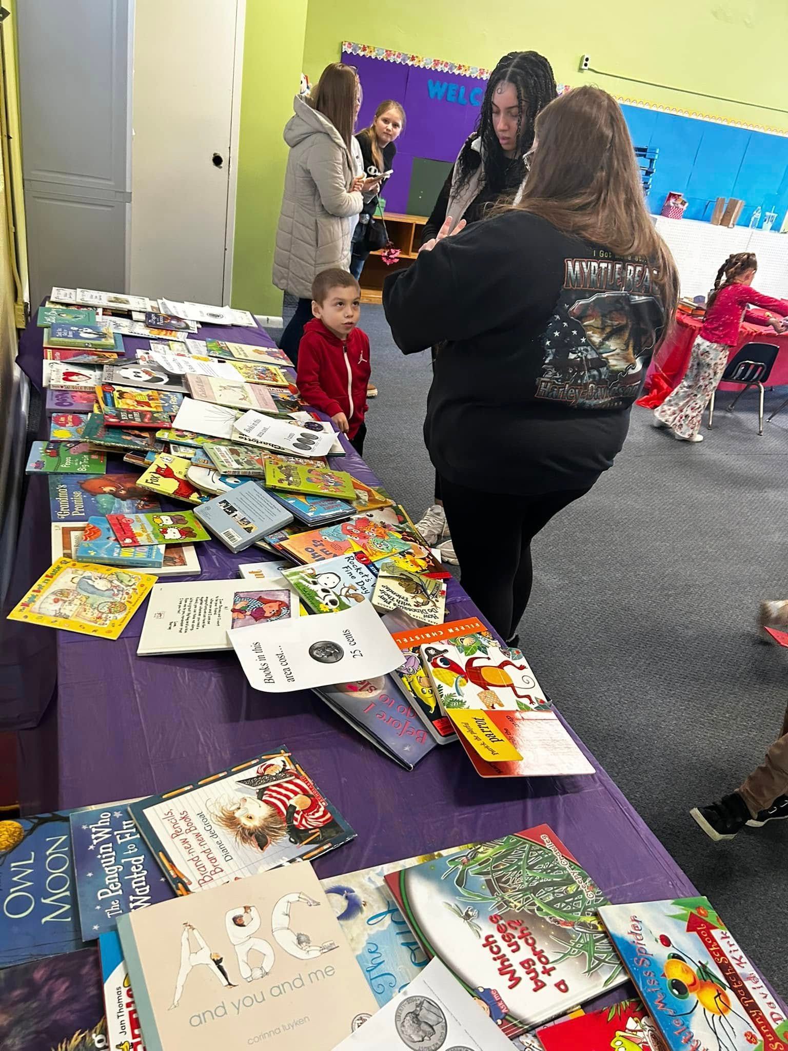A group of people are standing around a table filled with books.