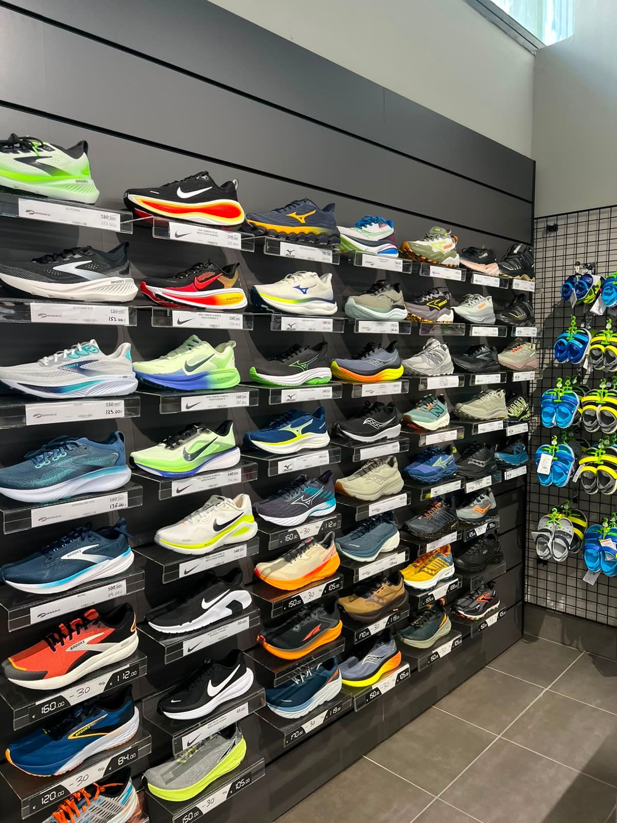 Grande parete espositiva con un'ampia selezione di scarpe da running tecniche e calzature ammortizzate per la corsa da Sport Service a Forlì.
