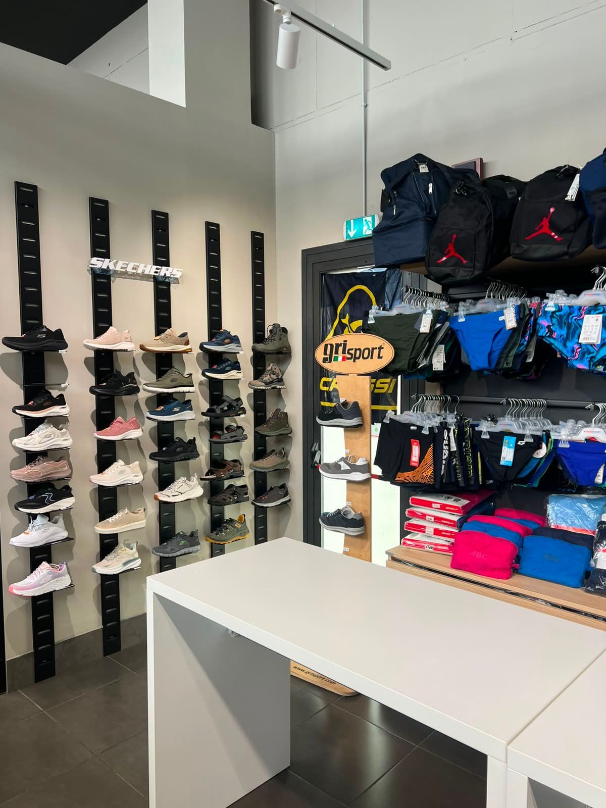 Esposizione con scarpe da running, calzature tecniche, zaini sportivi e accessori per l'allenamento da Sport Service a Forlì.