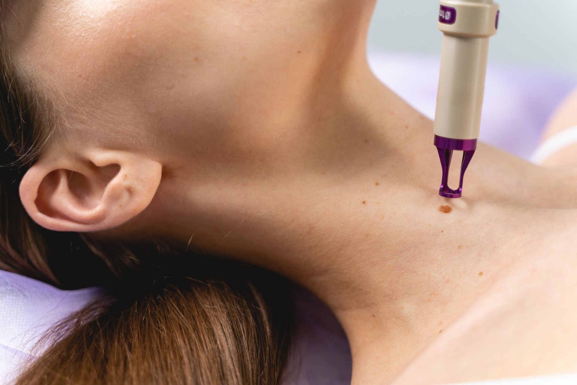 A woman is getting a laser treatment on her neck.