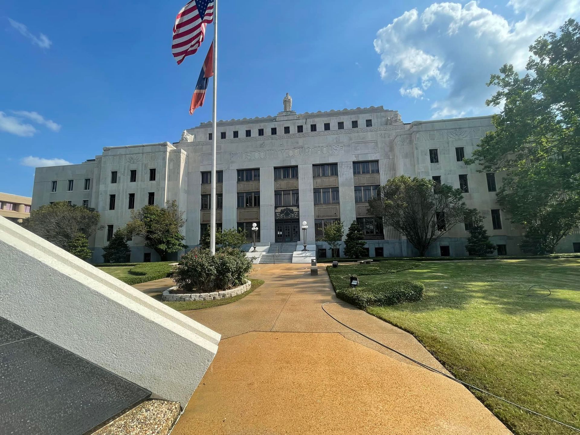 Courthouse with American and state flags flying; pathway leading to the entrance.