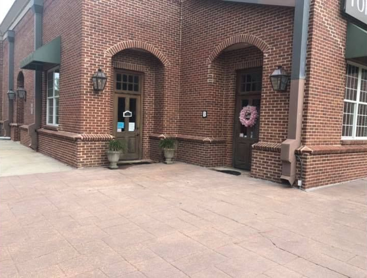 Red brick building with two arched doorways, each with a door and hanging sconce.
