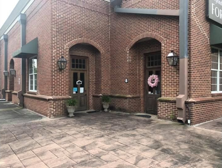 Brick building with arched doorways and a black awning over a window.