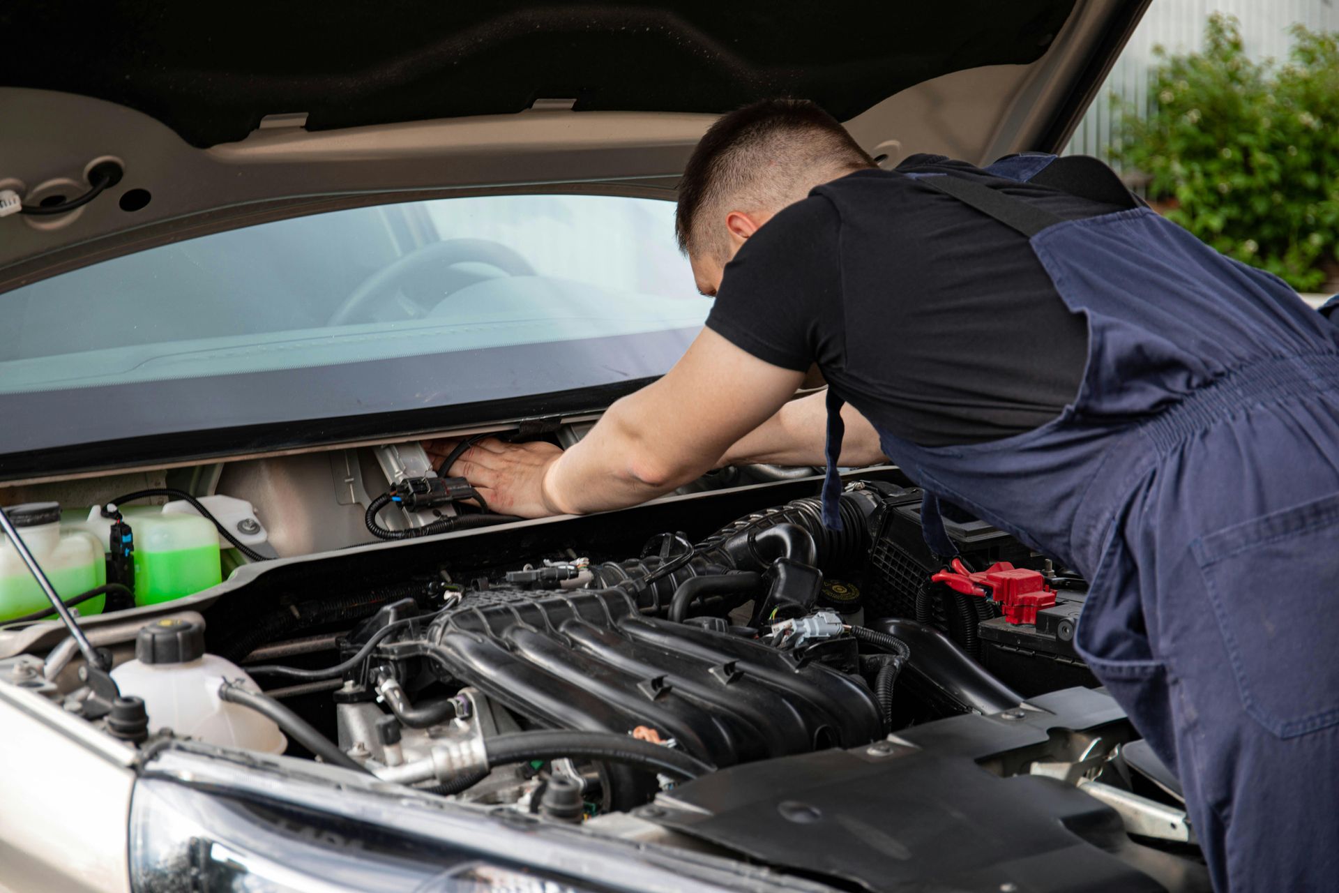 A man is working on the engine of a car with the hood open