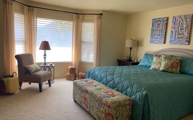 A Bedroom with A King Size Bed , Chair , Lamp and Window.