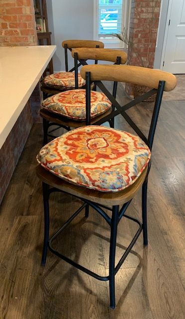 Three Bar Stools with Cushions on Them Are Sitting Next to Each Other in A Kitchen.