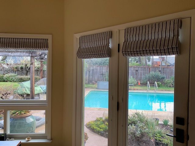 A Room with Two Windows and A Swimming Pool in The Background.