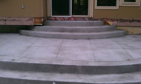Concrete steps and patio leading to a sliding glass door of a beige house.