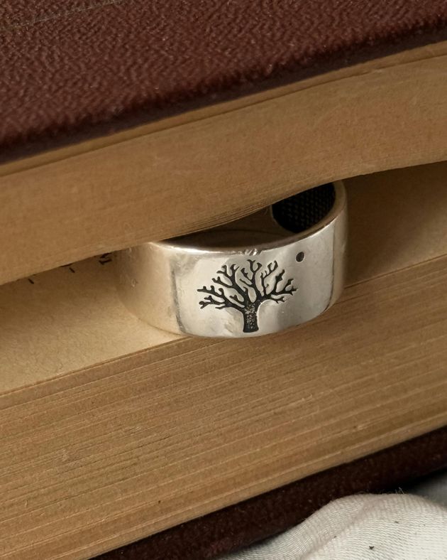 Un anello d'argento con un albero sopra è appoggiato sopra un libro