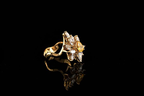 Un anello d'oro con una pietra gialla e diamanti su sfondo nero.