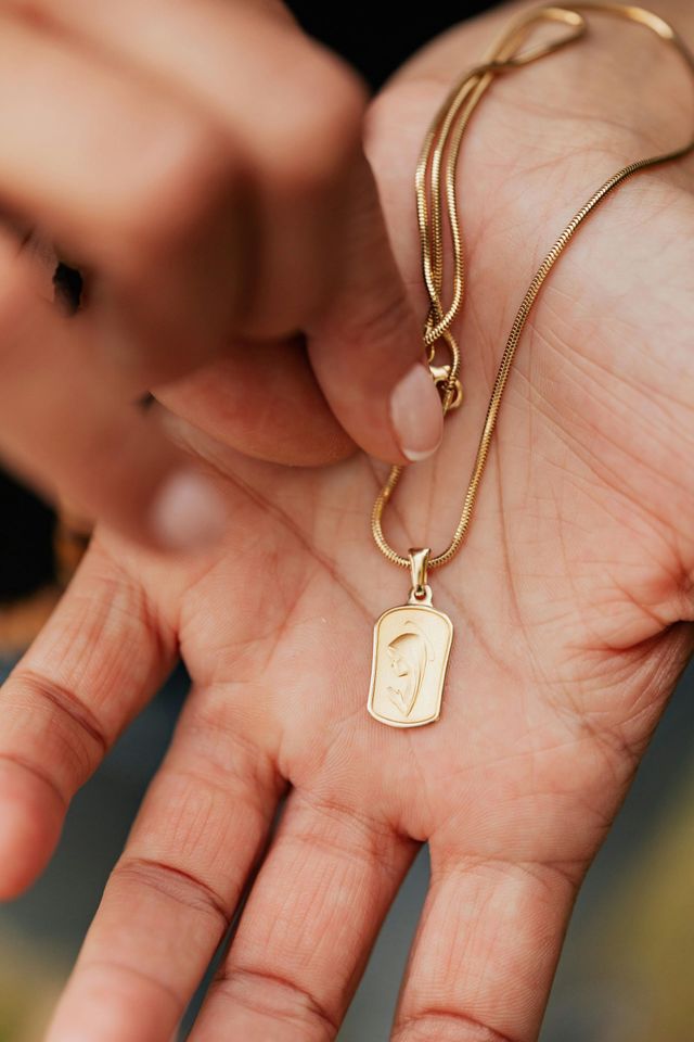 Una persona tiene in mano una collana d'oro.