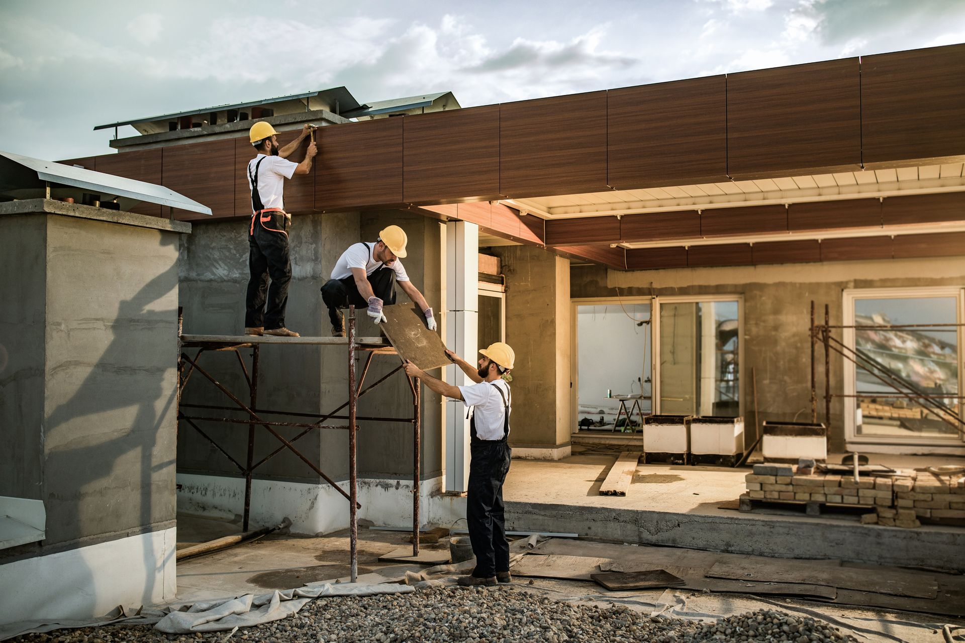 A team of workers collaborating on a home exterior renovation project.