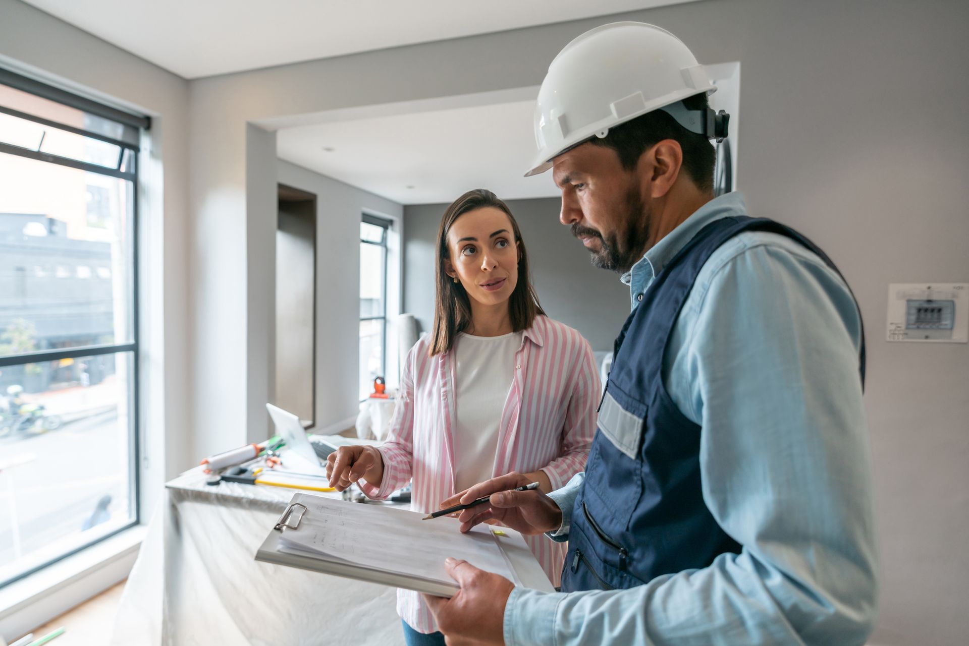 A woman talking to a contractor indoors while remodeling her house
