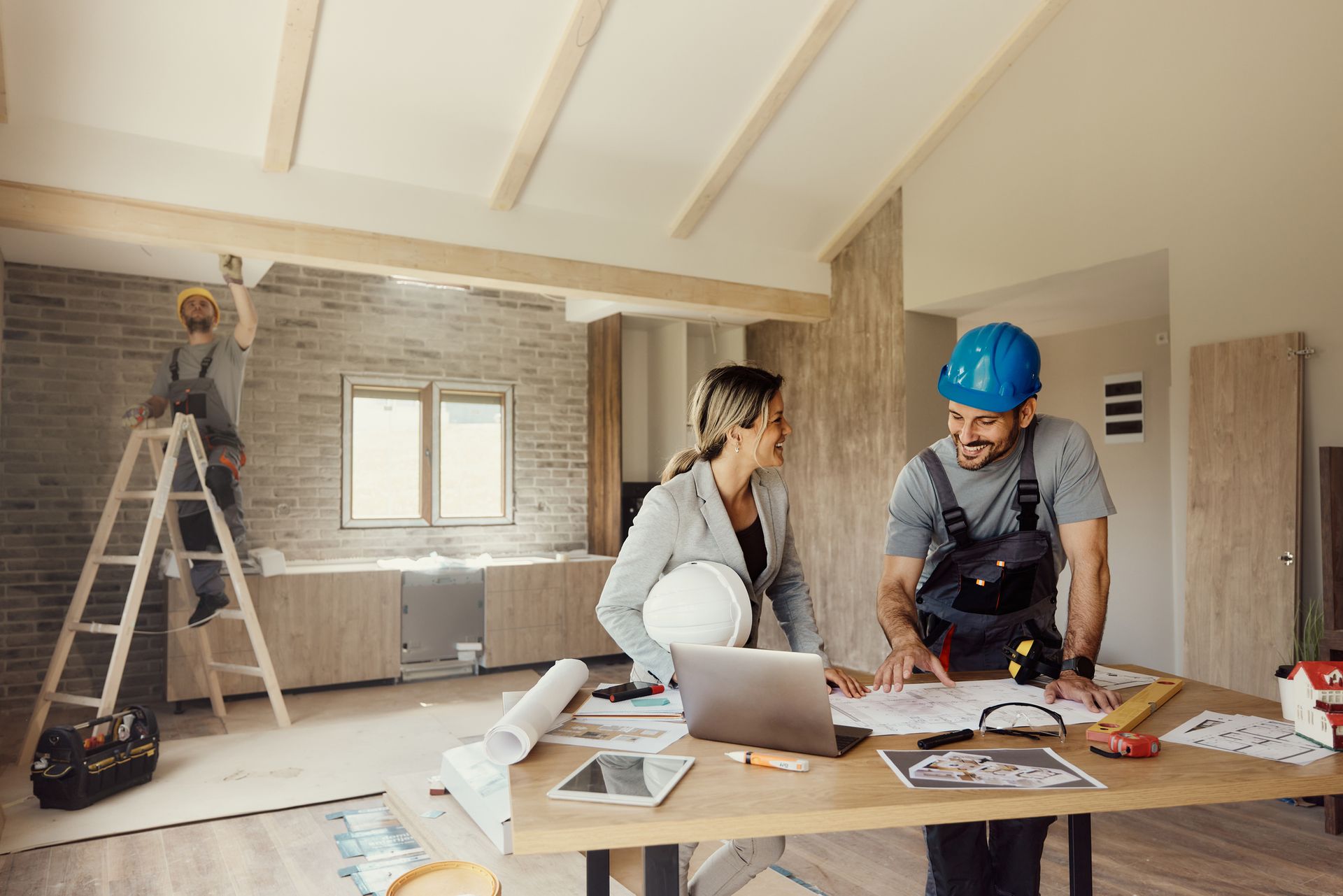 Happy female architect and worker discussing blueprints during interior house renovation. Happy female architect and worker discussing blueprints during interior house renovation.