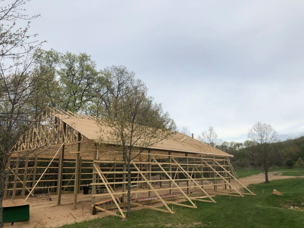 A large wooden building is being built in a field