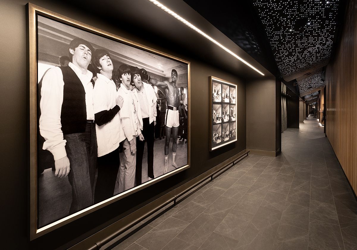 Illuminated decorative metal screen along a building exterior.