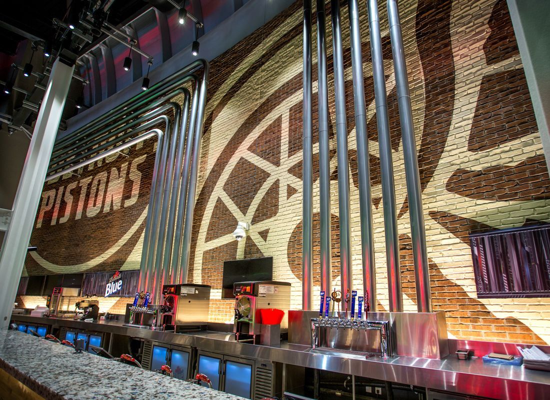 Bar with Pistons logo on wall, stainless steel pipes and counters.
