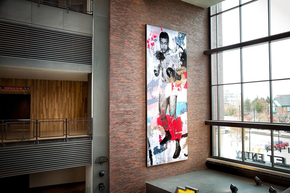 Artwork of a boxer on a textured wall next to a large window in a modern building.