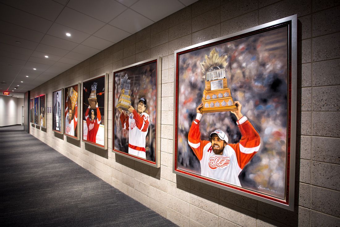 Hallway with framed paintings of Detroit Red Wings players holding the Stanley Cup.