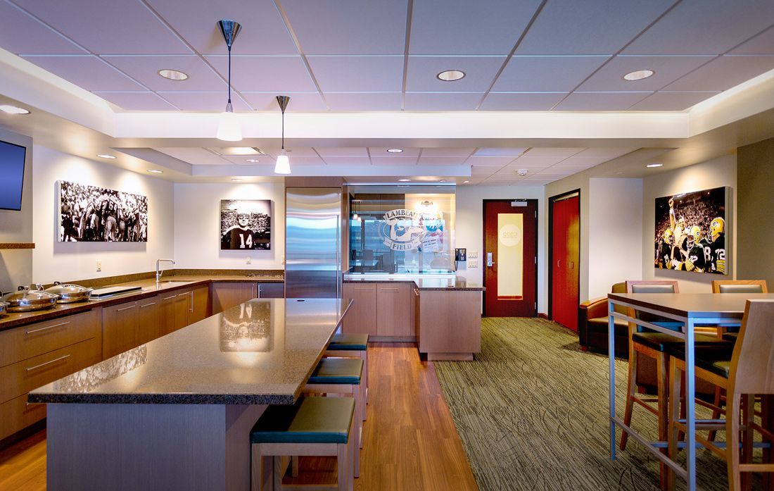 A modern break room with a long counter, stainless steel appliances, and a table with chairs.