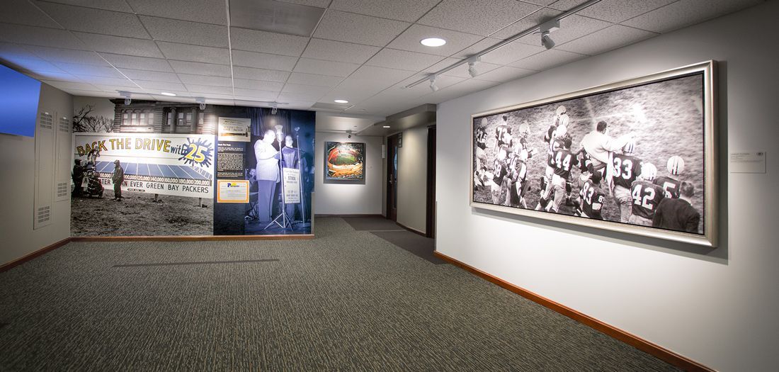 Gallery interior with large black and white photographs and displays on the walls, and carpeted floor.