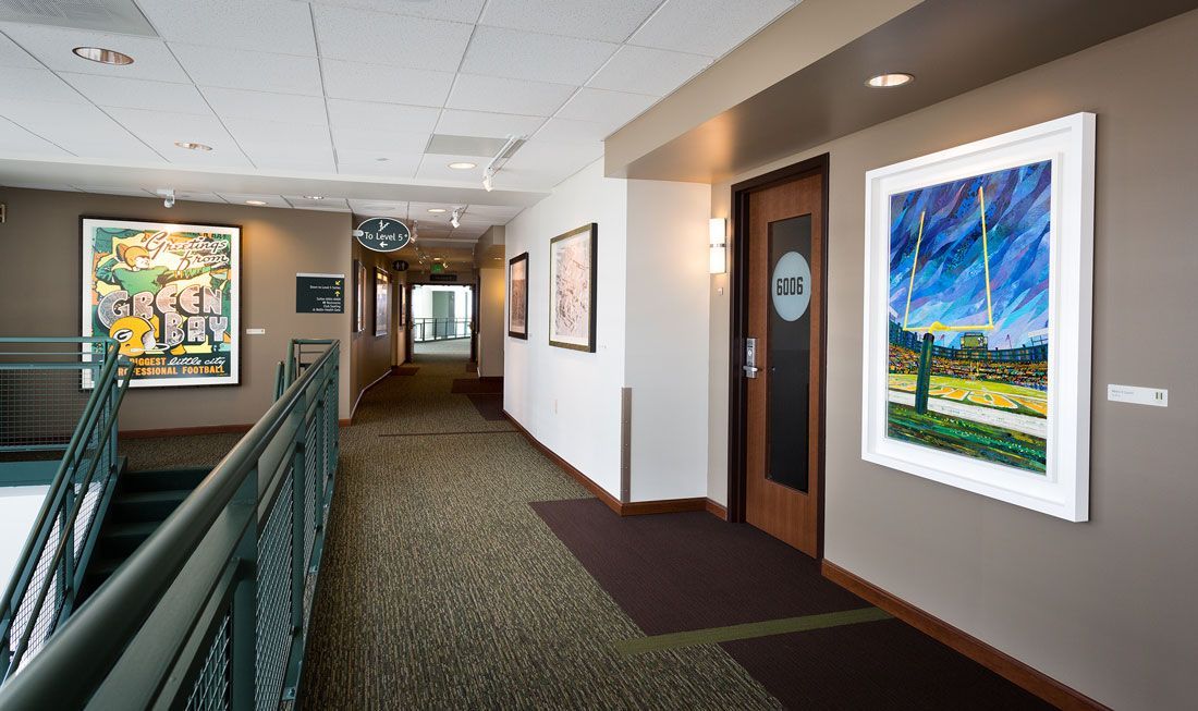 Hallway with art on the walls, green carpet, and a door with