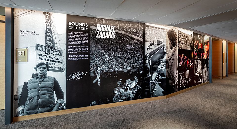 Hallway with black and white wall murals of people, concert scenes, and text.