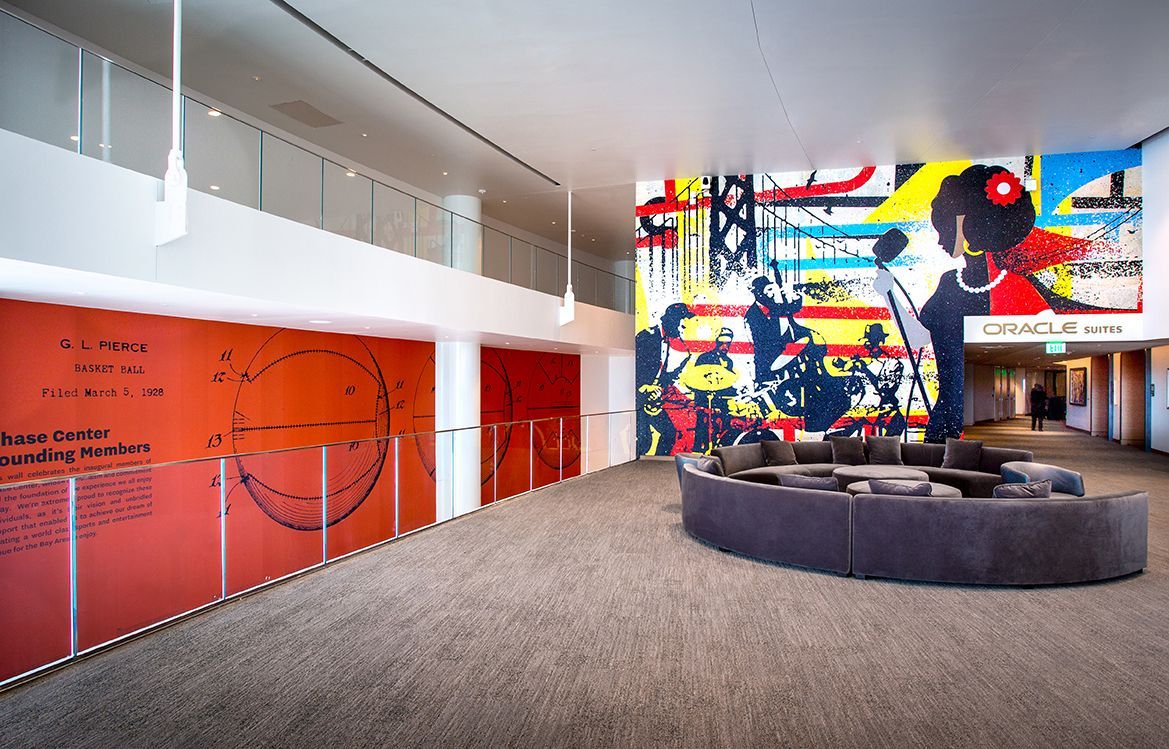 Large colorful mural and seating area in modern building lobby.