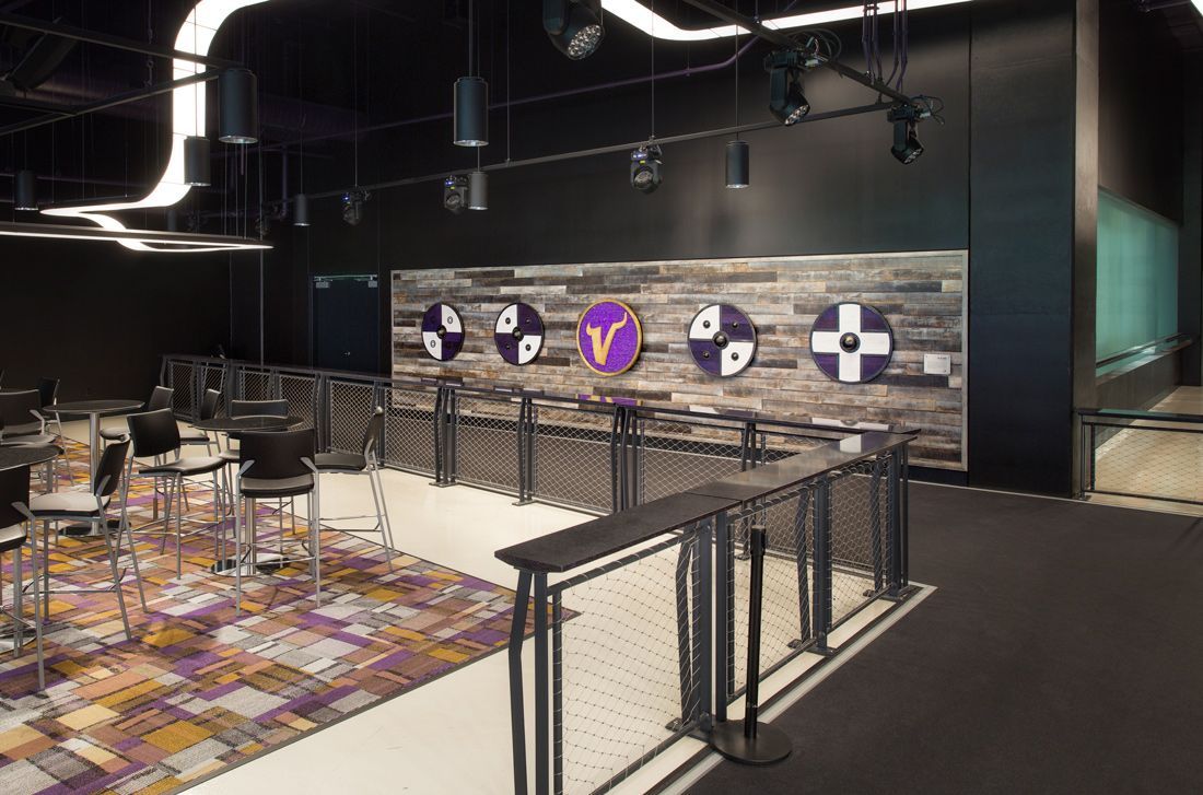 Interior view of a Vikings-themed lounge. Features include dart boards, bar stools, patterned carpet, and metal railings.