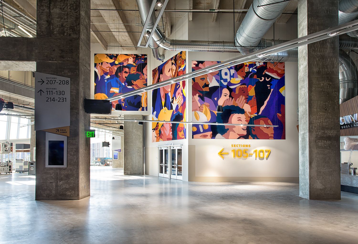 Hallway with large murals of a crowd, a yellow directional sign, and concrete pillars.