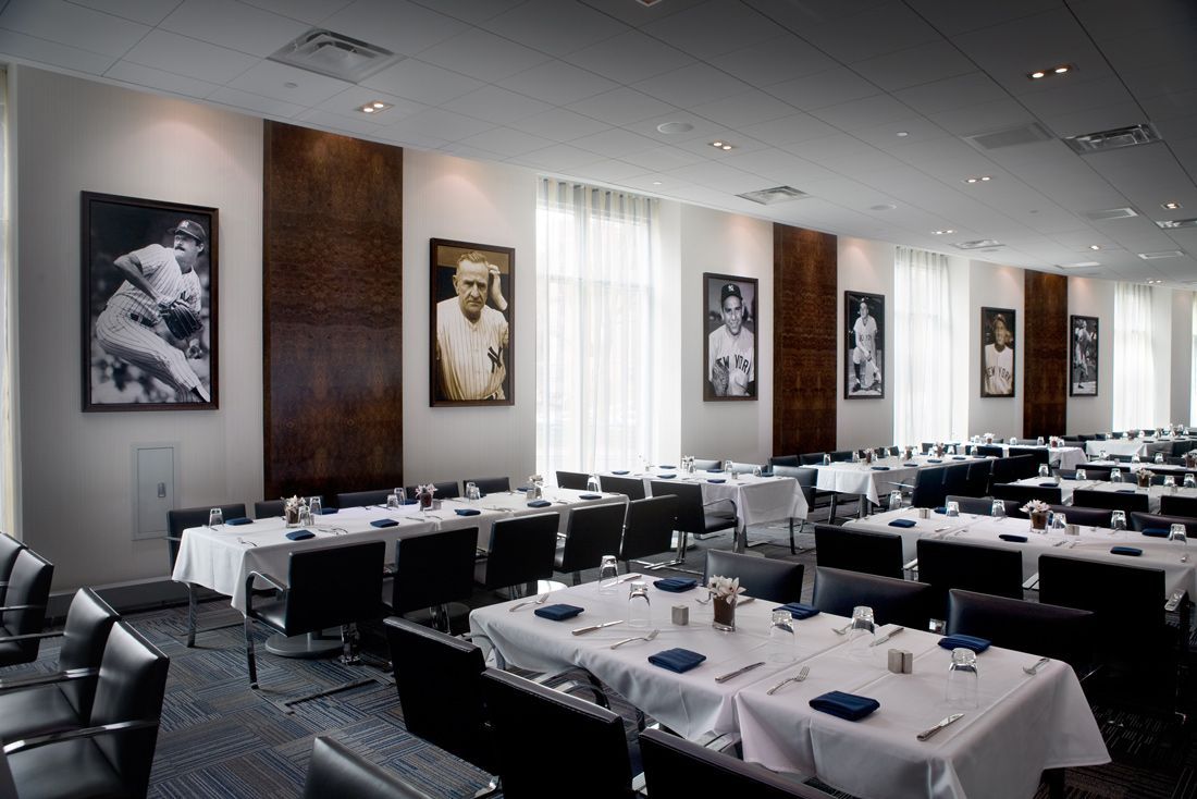 Dining room with tables set for guests, baseball player portraits on the wall, and dark chairs.