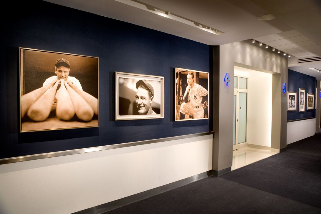 Hallway with framed photographs on dark blue walls; door at end.